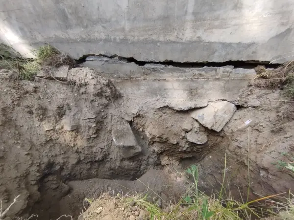 Fouille de fondation au pied d'un mur présentant des fissures